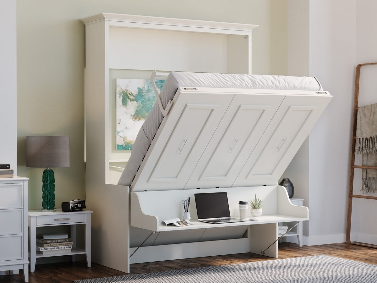 A white Murphy bed in a bright bedroom setting, shown with the bed frame open, partially showing the desk staying level. The room features light beige walls, a wooden floor, and a small white nightstand with a lamp on the left.