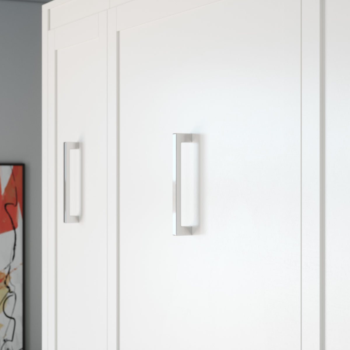 A close-up of the doors of a white Murphy bed with slim rectangular silver handles, shown in a clean interior setting.