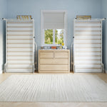 the room has a dresser, mirror, and two liftable beds up against a light blue wall.